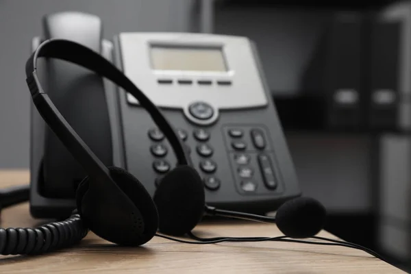 Ofisteki Ahşap Masanın Yanındaki Sabit Telefonun Yanında Modern Kulaklık Yakın — Stok fotoğraf