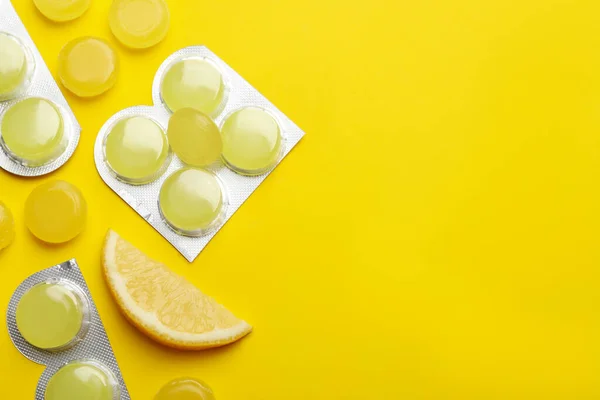 Many lemon cough drops on yellow background, flat lay. Space for text