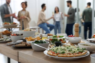 Farklı lezzetli yemekler ve arka planda bulanık insanlar olan kahvaltı masası.