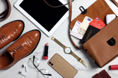 Beyaz mermer zemin üzerinde dökümanlar, para ve aksesuarlar ile düz kompozisyon yatıyordu. İş gezisi için toplanıyorum.