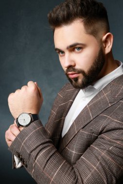 Siyah arka planda şık takım elbiseli yakışıklı sakallı adam.