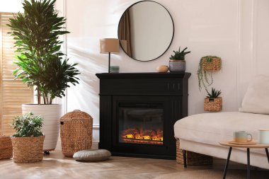 Şık bir oturma odası. İçinde elektrikli şömine, rahat bir kanepe ve güzel dekorasyon unsurları var.