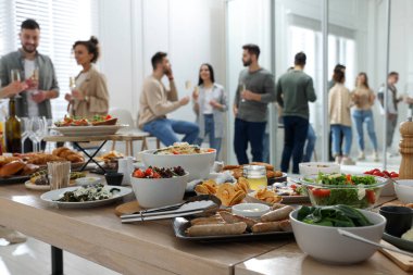 Brunch table setting with different delicious food	and blurred view of people on background