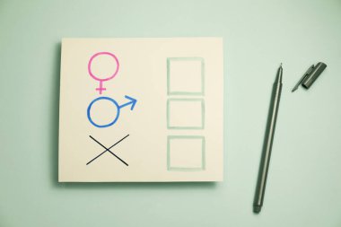 Cinsiyet eşitliği. Kartın yanındaki işaretli kalem, açık gri arka planda erkek ve kadın sembolleri, düz yatıyordu.