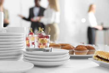 Farklı lezzetli atıştırmalıklar ve bulaşık takımlarıyla dolu bir masa. Kahve molası