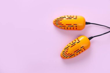 Mor arka planda modern elektrikli ayakkabı kurutma makinesi, üst manzara. Metin için boşluk