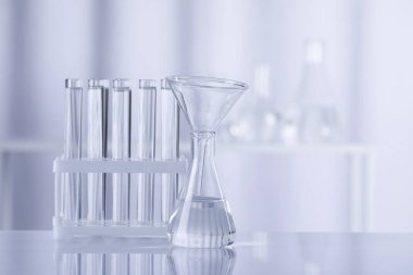 Bulanık arka planda şeffaf sıvı bulunan farklı bir laboratuar cam. Metin için boşluk