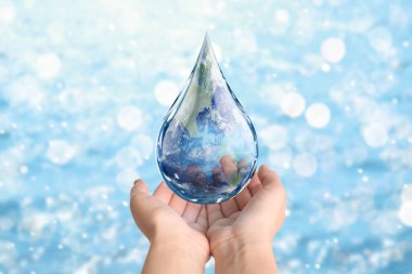 Dünya Su Günü. Bulanık arkaplanda Dünya görüntüsü olan indirme simgesini tutan kadın, yakın plan