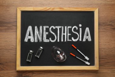 Tahtada kelime anestezi, tüpler, maske ve şırıngalar tahtada.