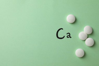 Açık yeşil zemin üzerinde kalsiyum takviye hapları ile düz konum, metin için boşluk