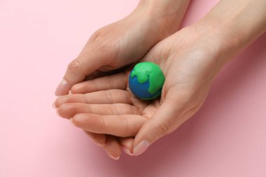 Gezegen modelini pembe arka planda tutan kadın, yakın plan. Dünya Günü