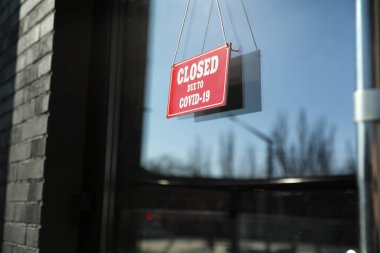 Camda asılı duran Covid-19 nedeniyle kapalı olan kırmızı tabela. Coronavirus karantinası