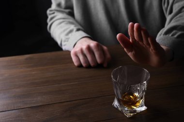 Ahşap masada viski içmeyi reddeden adam, yakın plan. Alkol bağımlılığı