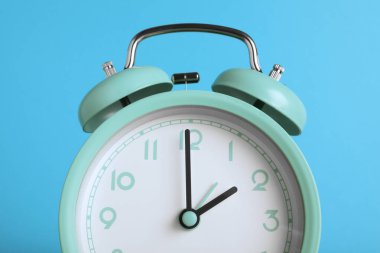 Açık mavi arkaplanda turkuaz alarm saati, yakın plan