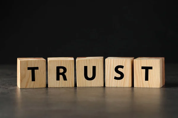 Word Trust Made Wooden Cubes Grey Table Black Background — Stock Photo, Image