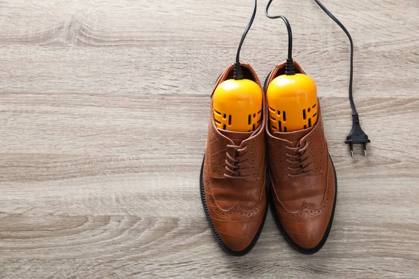 Pair Stylish Shoes Modern Electric Footwear Dryer Wooden Background Top — Zdjęcie stockowe