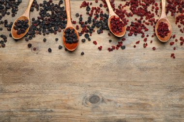 Kurutulmuş kırmızı ve siyah frenk üzümü ahşap masada, düz yerde. Metin için boşluk