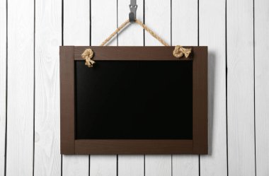 Beyaz ahşap duvarda asılı temiz, küçük siyah bir karatahta.