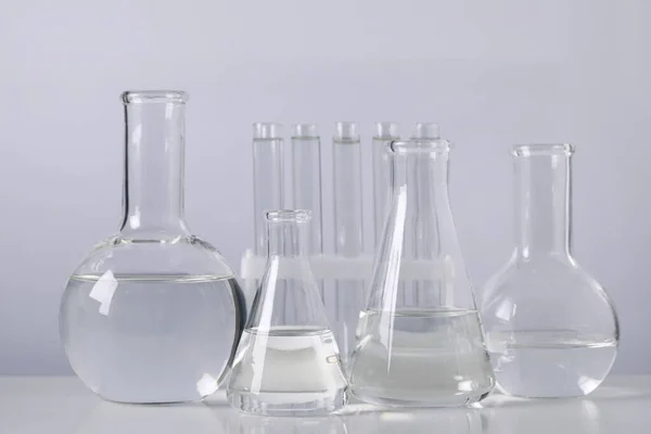 Different Laboratory Glassware Transparent Liquid Table Light Background — ストック写真