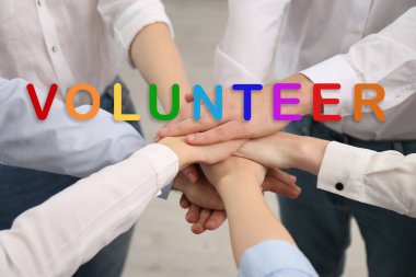 Gönüllüler el ele tutuşuyor, kapalı alanda, yakın çekim.