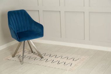 Odadaki ışık duvarının yanındaki şık mavi koltuk. Metin için boşluk