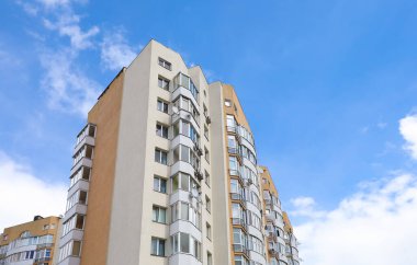 Mavi gökyüzüne karşı çok katlı apartmanın dışı, alçak açılı.