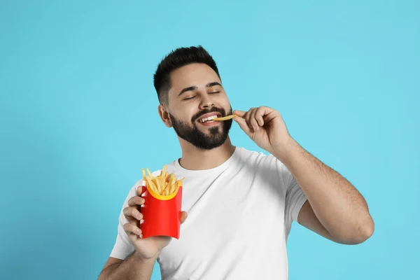 Jeune Homme Mangeant Des Frites Sur Fond Bleu Clair — Photo