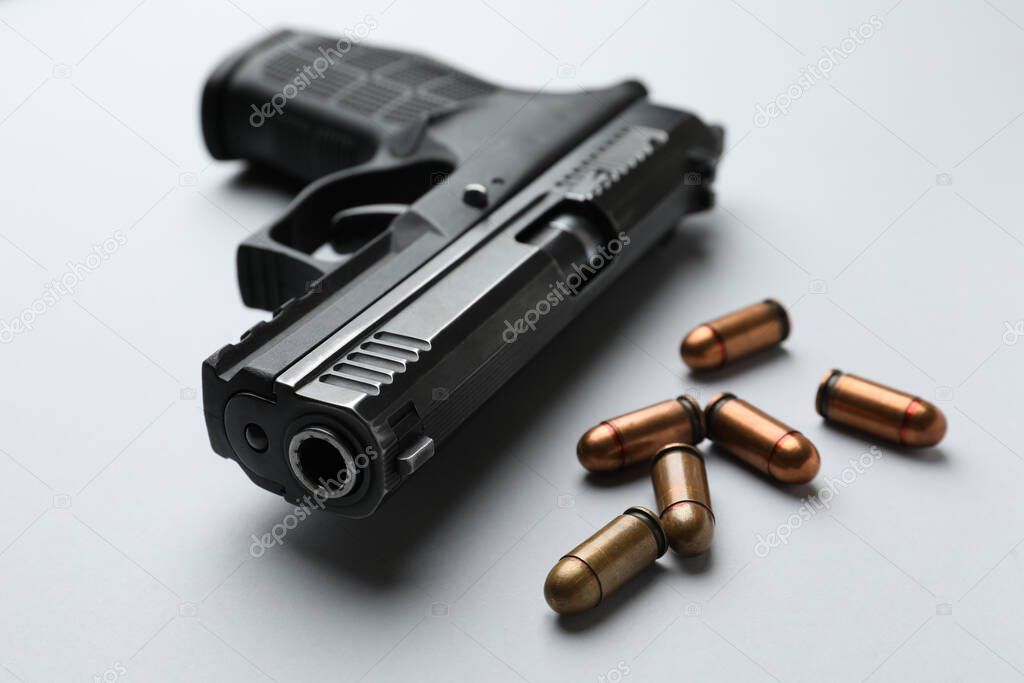 Semi-automatic pistol and bullets on light background, closeup