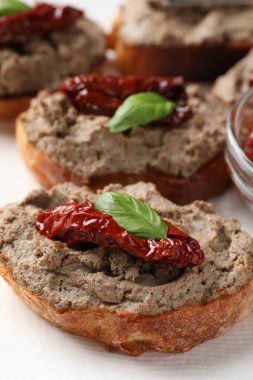 Lezzetli ezmeli ekmek dilimleri, kurutulmuş domates ve peçeteli fesleğen, yakın plan.