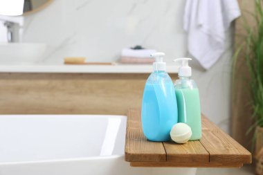 Duş jeli dolu ahşap tepsi ve banyo bombası küvette, mesaj için yer.
