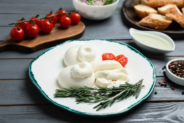 Biberiyeli lezzetli burrata peyniri ve gri ahşap masada servis edilen domates.