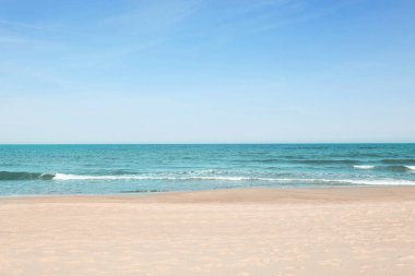 Güneşli bir günde güzel deniz ve kumlu plaj manzarası.