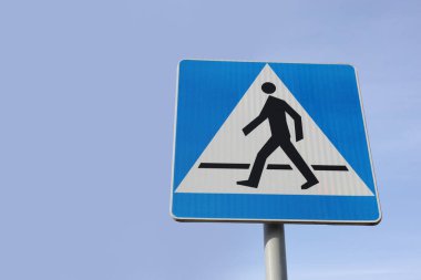 Trafik levhası mavi gökyüzüne karşı yaya geçişi, alçak açı. Metin için boşluk