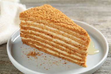 Ahşap masada servis edilen lezzetli katmanlı ballı kek dilimi.