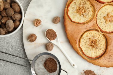 Nutmeg tozu, tohum ve lezzetli elmalı turta açık gri masada, düz yerde.