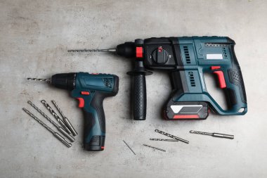 Açık gri masa üzerinde bükülmüş parçalarla modern elektrik matkapları, düz konum