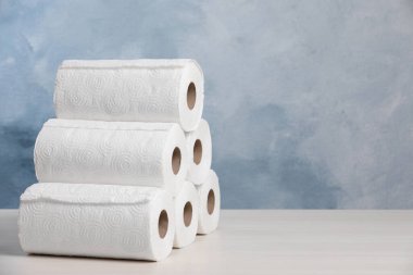 Many rolls of paper towels on white wooden table. Space for text