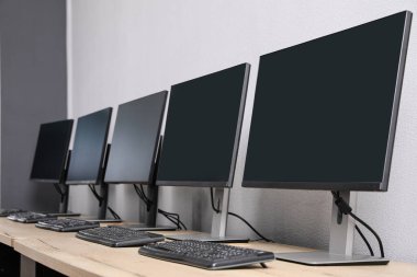 Ofisin içini aç. Açık gri duvarın yanında bilgisayarları olan modern işyerleri