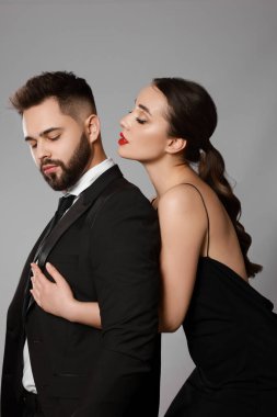 Gri arka planda seksi bayan olan yakışıklı sakallı adam.