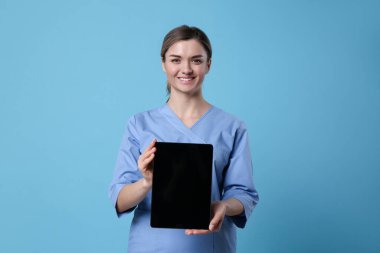 Açık mavi arkaplan üzerinde boş tablet tutan doktor tasarım için boşluk