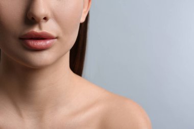Açık gri arka planda dudakları olan güzel bir kadın, yakın plan. Metin için boşluk