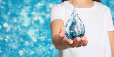 Dünya Su Günü. Bulanık arkaplanda Dünya görüntüsü olan indirme simgesini tutan kadın, yakın plan