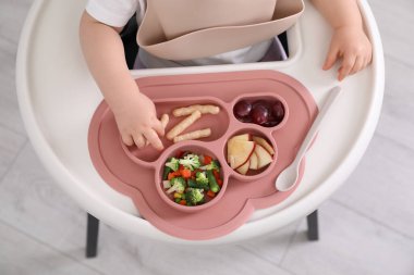 Küçük bebek mutfakta yüksek sandalyede yemek yiyor, yakın plan. Üst görünüm