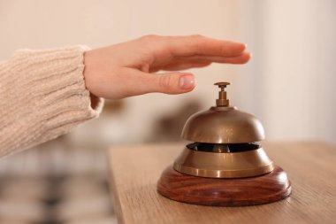 Ahşap resepsiyonda otelin servis zilini çalan kadın, yakın plan.