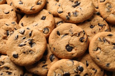Many delicious chocolate chip cookies as background, top view