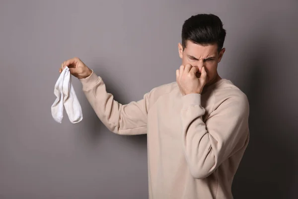 Man Feeling Bad Smell Dirty Socks Grey Background — Stock Photo, Image