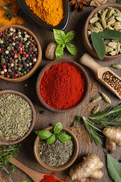 Different herbs and spices on wooden table, flat lay