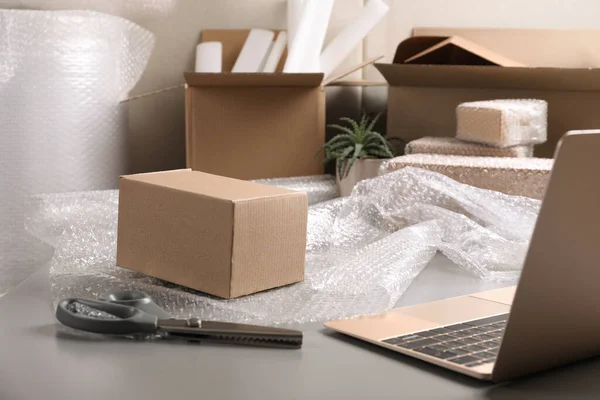 Table with laptop, boxes and bubble wrap in warehouse