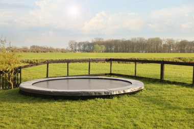 Croquet equipment and shoes near trampoline on green grass outdoors