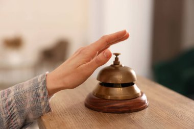 Ahşap resepsiyonda otelin servis zilini çalan kadın, yakın plan.